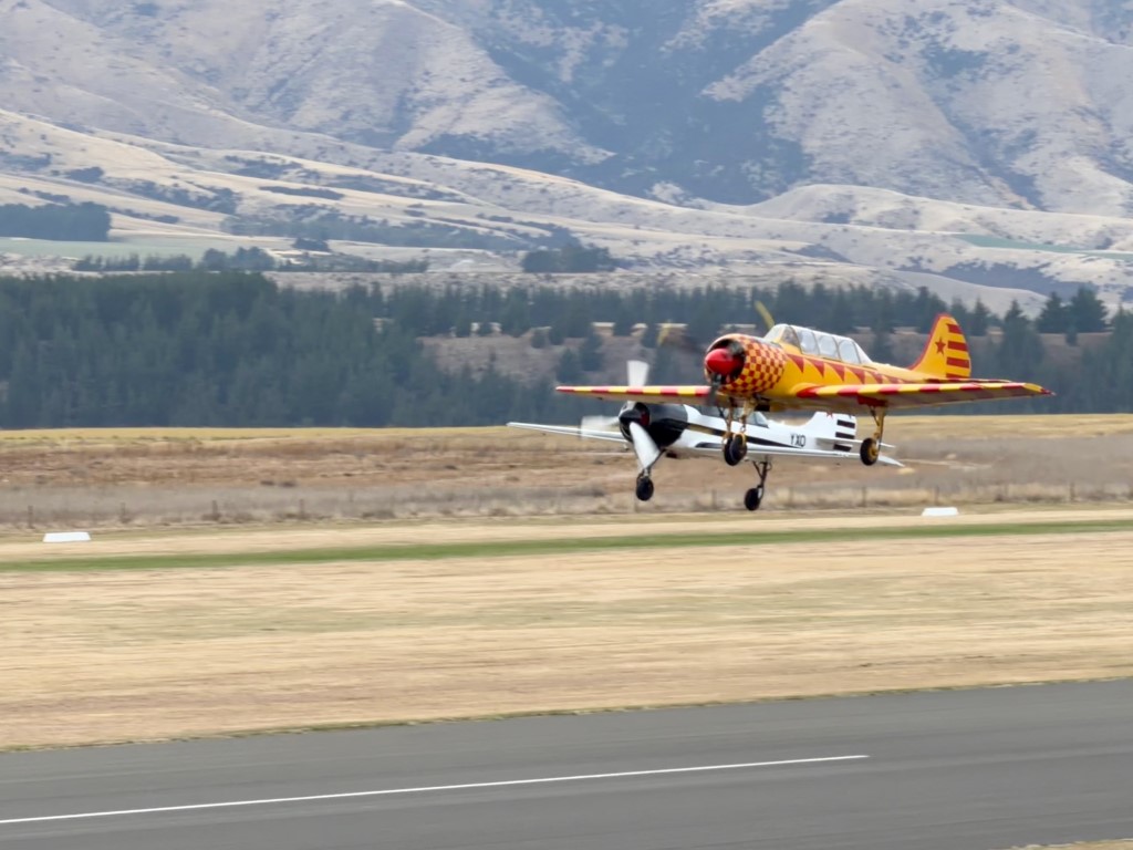 A pair of Yakovlev Yak-52s lift off together during the Warbirds Over Wanaka display. Originally designed as a Soviet military trainer,  the Yak-52 is powered by a 360 hp Vedeneyev nine-cylinder radial engine and is a highly capable aerobatic aircraft. 